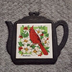 vintage teapot-shaped cast iron and ceramic trivet featuring a cardinal design. 